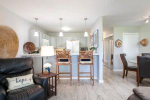 a living room and kitchen with a couch and chairs at Tropical condo with pools lanai & BBQ in Waikoloa Village