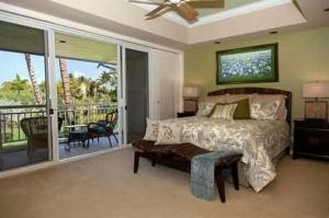 a bedroom with a bed and a balcony at Spacious retreat with pool & private lanai in Waikoloa