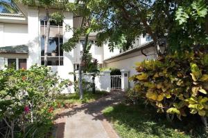 a white house with a tree and a driveway at Spacious retreat with pool & private lanai in Waikoloa