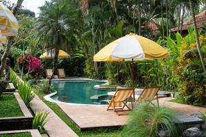 a pool with two chairs and an umbrella at Shelter Island in Ubud