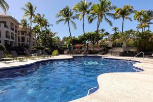 a swimming pool with palm trees in a resort at Tropical 1BR condo with pool & private lanai in Waikoloa