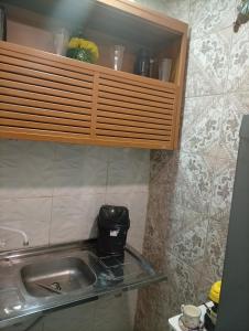 a kitchen with a sink and a coffee maker on a shelf at Flat aconchegante na maraponga in Fortaleza