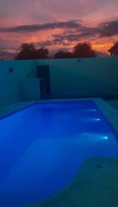 een zwembad met blauw licht voor een zonsondergang bij Quincho Russo in Cerrillos +3 foto's