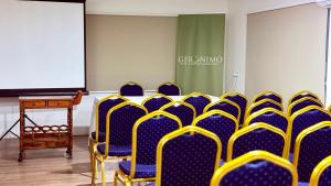 ein Konferenzraum mit blauen und gelben Stühlen und einem Bildschirm in der Unterkunft Hotel Geronimo in Pucón