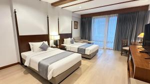 ein Hotelzimmer mit zwei Betten und einem Fernseher in der Unterkunft Belle Villa Resort, Chiang Mai in Ban Pong