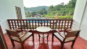 ein Balkon mit Tisch und Stühlen und Blick auf einen Pool in der Unterkunft Belle Villa Resort, Chiang Mai in Ban Pong