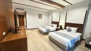 ein Hotelzimmer mit zwei Betten und einem Fernseher in der Unterkunft Belle Villa Resort, Chiang Mai in Ban Pong