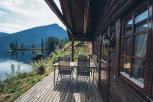 a deck with chairs and a table and a view of a lake at Strandbu in Viksdalen