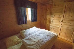 a bed in a wooden room with a window at Strandbu in Viksdalen