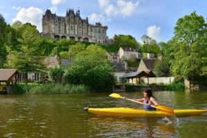 a woman in a kayak on a river with a castle at Kasaloc in Maintenon