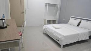 una camera da letto con un letto bianco, una scrivania e una sedia di TharaD place a Samut Sakhon