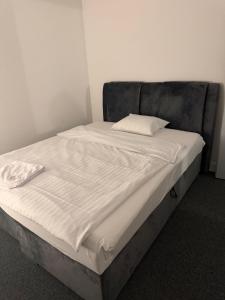 ein Bett mit weißer Bettwäsche und einem Kissen darauf in der Unterkunft Lindas Apartment in Dietlikon