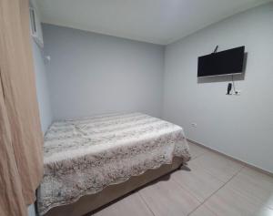 een slaapkamer met een bed en een flatscreen-tv bij Casa Aconchegante in Guarujá