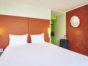 ein Schlafzimmer mit einem großen Bett und einem Koffer in der Unterkunft Greet Hotel Versailles - Voisins Le Bretonneux in Voisins-le-Bretonneux + 69 Fotos