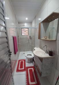 een badkamer met een toilet, een wastafel en een douche bij Casa Aconchegante in Guarujá