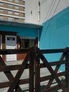 een houten hek voor een blauw gebouw bij Depto 2 ambientes A pasos del MAR in Mar de Ajó