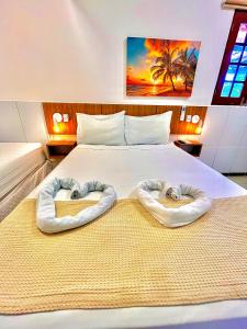 een slaapkamer met een bed met twee handdoeken erop bij Pousada La Riviera - Pé na areia e Passeios em Maragogi in Maragogi