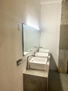 een badkamer met 3 wastafels en een grote spiegel bij surf swell hostel in Weligama