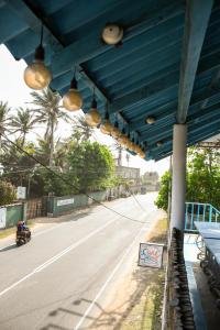 een blauw dak boven een weg met een motorfiets bij surf swell hostel in Weligama +9 foto's