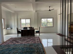 een woonkamer met een tafel, stoelen en ramen bij Mangal Uday Villa in Jaipur