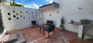 a patio with three chairs and a white wall at Loft Colibrí en Centro Histórico Carmen in Ciudad del Carmen
