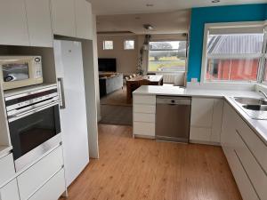 a kitchen with white appliances and a living room at Cbay Executive Accommodation in Timaru