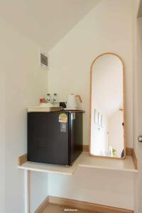 een keuken met een spiegel en een zwarte koelkast bij กู๊ดวิวแคมป์ชะอม in Ban Bung Mai