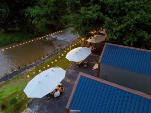 a group of people sitting under umbrellas near a river at กู๊ดวิวแคมป์ชะอม in Ban Bung Mai