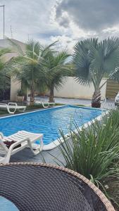 a swimming pool with two chairs and palm trees at Casas Paradisiaca aleatória l , ll ou lll ou lV Pagamento Automática in Caldas Novas