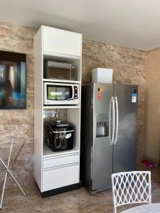 a kitchen with a refrigerator and a microwave at Casas Paradisiaca aleatória l , ll ou lll ou lV Pagamento Automática in Caldas Novas