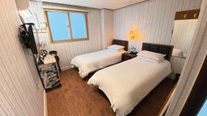 une chambre d'hôtel avec deux lits et une fenêtre dans l'établissement Friendly DH Naissance Hotel by Mindrum Group, à Séoul