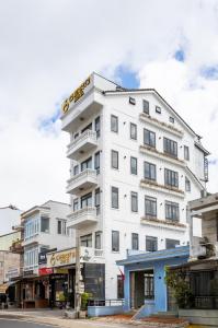 a white building with balconies on a city street at Cherry Hotel 2 Da Lat in Da Lat