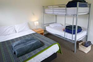 een slaapkamer met een bed en een stapelbed bij Mt Aspiring Holiday Park in Wanaka