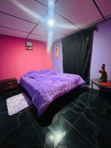 - une chambre avec un lit violet et une table dans l'établissement Casa Colores, à Murillo