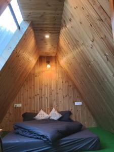 a bed in a room with a wooden ceiling at The Clifton chapter tirthan in Gushaini