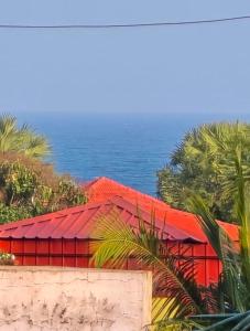 a red house with the ocean in the background at The Dreams sea view in Puducherry