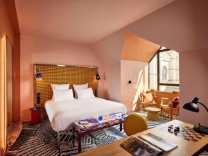 a bedroom with a bed and a table in a room at Mama Shelter Dijon in Dijon