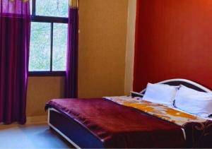 Schlafzimmer mit einem Bett mit roten Wänden und einem Fenster in der Unterkunft Kanara Hotel in Bhīm Tāl