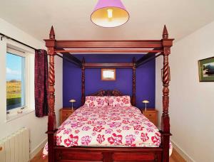 a bedroom with a canopy bed with a purple wall at Beinn Edra apartment in Staffin