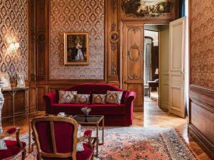 ein Wohnzimmer mit einem roten Sofa und einem Tisch in der Unterkunft Abbaye Des Vaux De Cernay in Cernay-la-Ville