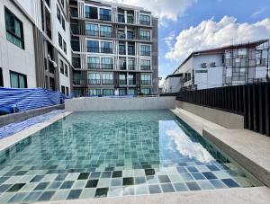 a swimming pool in front of a tall building at Z cape 1 two two in Ban Thalat Choeng Thale