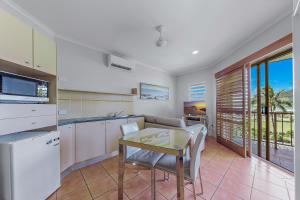 een keuken met een tafel en een eetkamer bij Spa Haven 18B in Airlie Beach