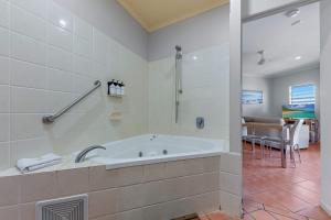 een grote badkamer met een bad en een eetkamer bij Spa Haven 18B in Airlie Beach
