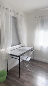 a table and a chair in a room with curtains at Pretty bedroom with shared bathroom in Hacienda Heights