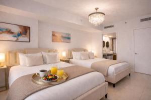a hotel room with two beds and a tray with fruit on it at Brickell 35th Floor Residence with Saltwater Pool 5-Star Amenities in Miami