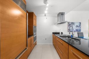 a kitchen with wooden cabinets and a sink at Brickell 35th Floor Residence with Saltwater Pool 5-Star Amenities in Miami +29 photos