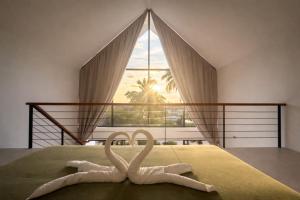 twee witte zwanen op een bed in een slaapkamer bij Sumba Luxury Cottages Pool & Jacuzzi in Ko Pha Ngan