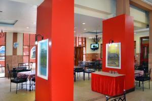 un restaurante con columnas rojas, mesas y sillas en Arusha Naaz Hotel, en Arusha