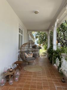 a porch with a wicker chair on a patio at BellaDonna By The Bay in Bridgetown
