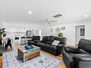 een woonkamer met een zwarte leren bank en een tafel bij Tenang Escape Yarrawonga in Yarrawonga